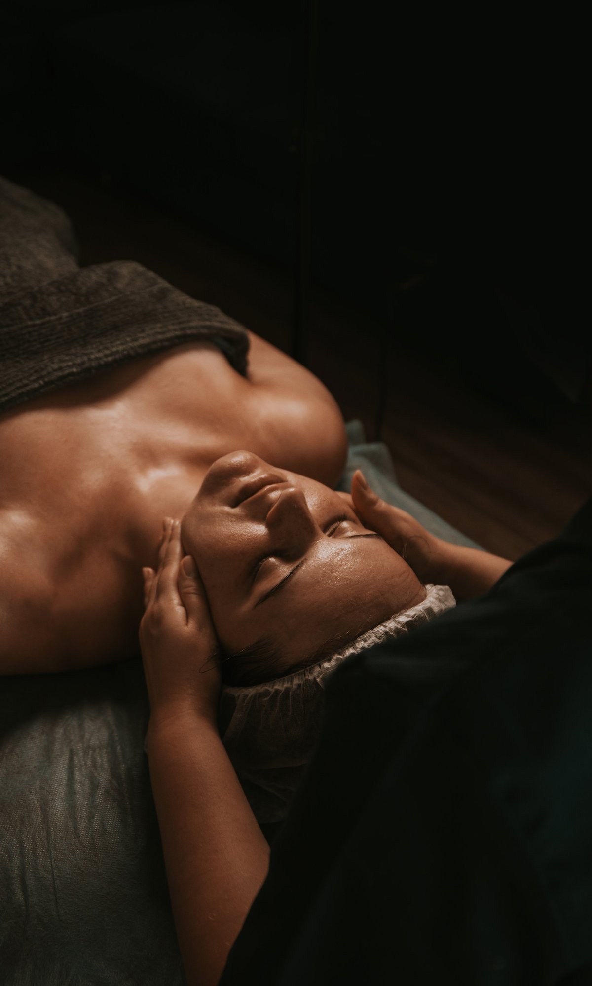 Woman receiving facial massage in a dimly lit spa setting