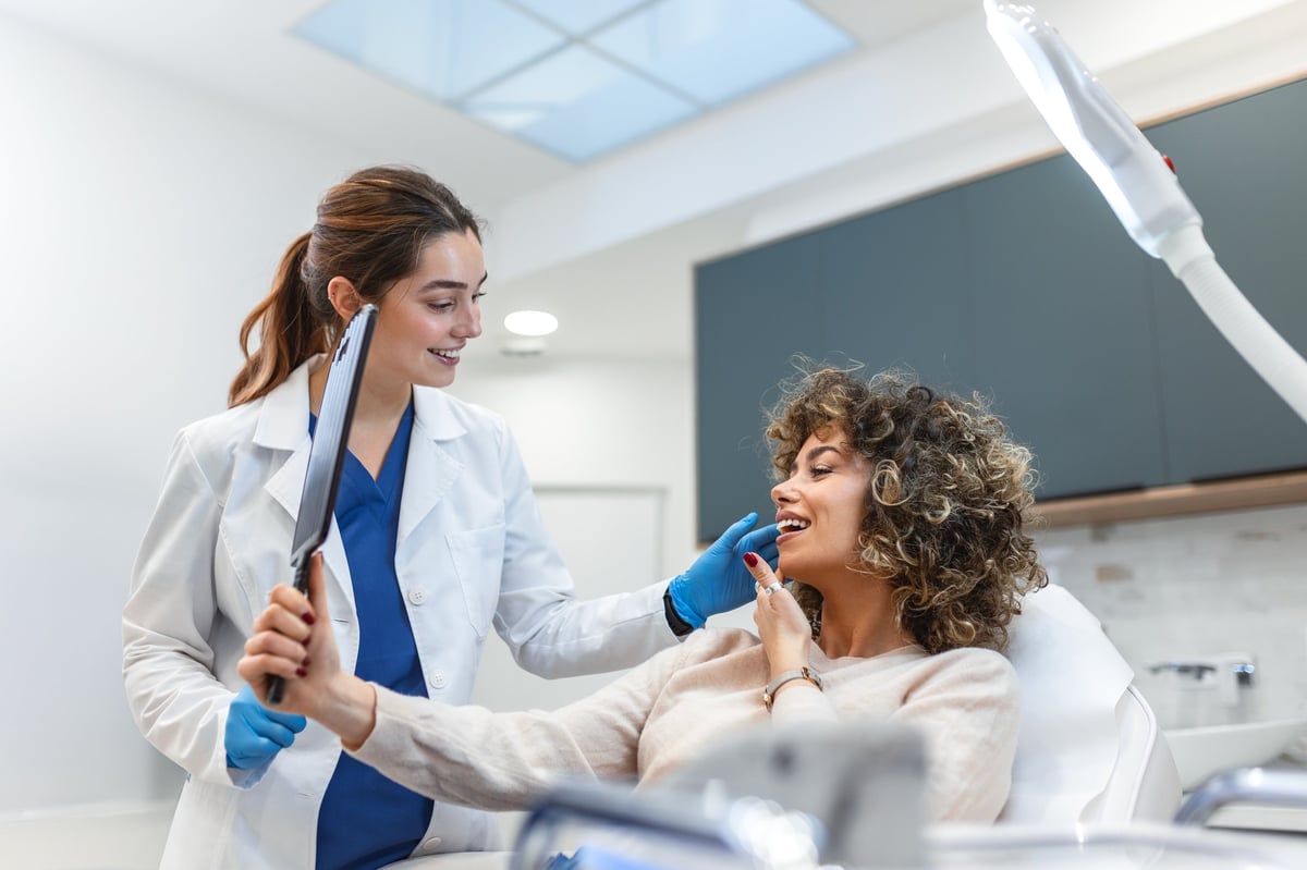 Patient looking at treatment results in mirror with a professional aesthetic medical consultant